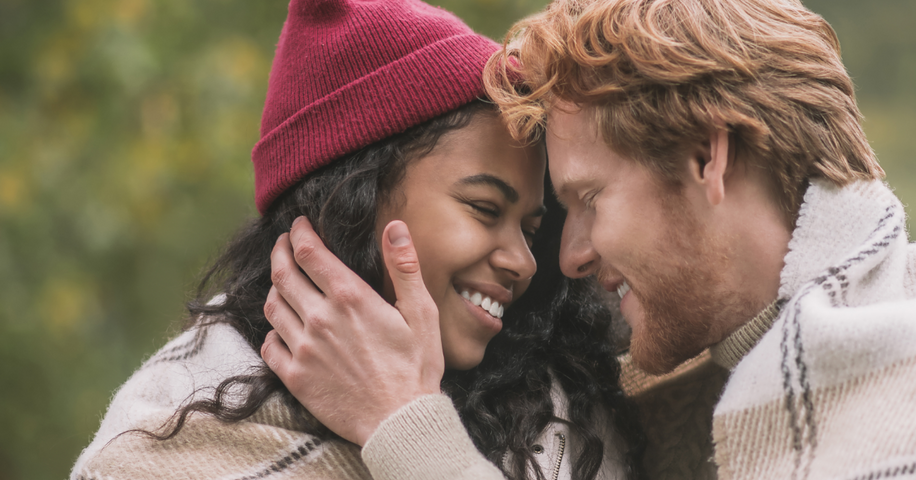 Man caressing woman’s face as they lean closer together while smiling. 