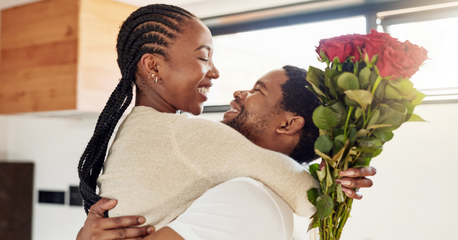 Woman clutching a bouquet of roses while being held by her partner.