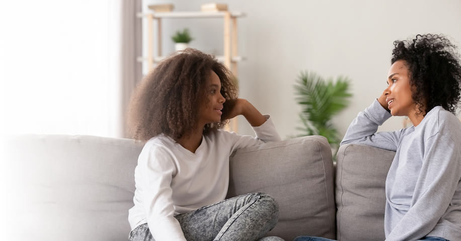 Une mère et sa fille, assises sur un sofa, discutent de santé sexuelle.