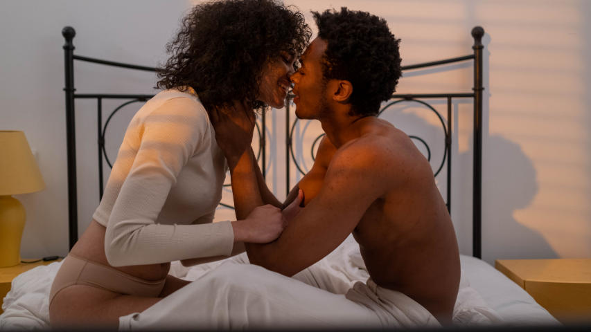Couple s’embrassant au lit lors d’une soirée pyjama sexy.