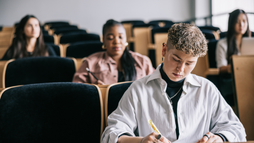 Des étudiant.e.s prennent des notes dans un cours d’éducation sexuelle donné dans un amphithéâtre.