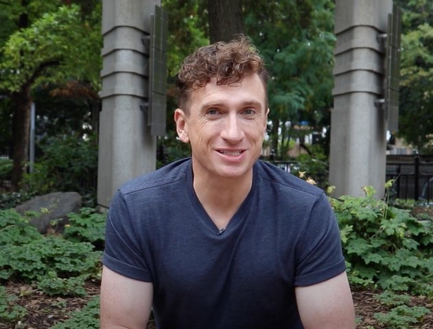 Brock McGillis wearing a navy T-shirt speaking into the camera