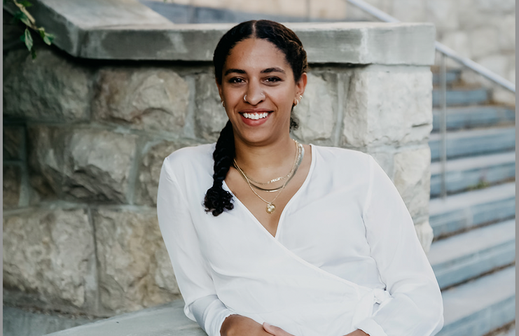 Natalya Mason adossée à un bâtiment de pierre et souriant à l’appareil photo.