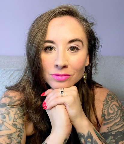 Headshot of Erica Smith wearing pink lipstick and a gold feather earring