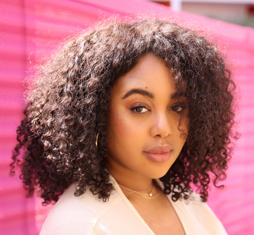 Portrait de Shadeen Francis adossée à une clôture rose.