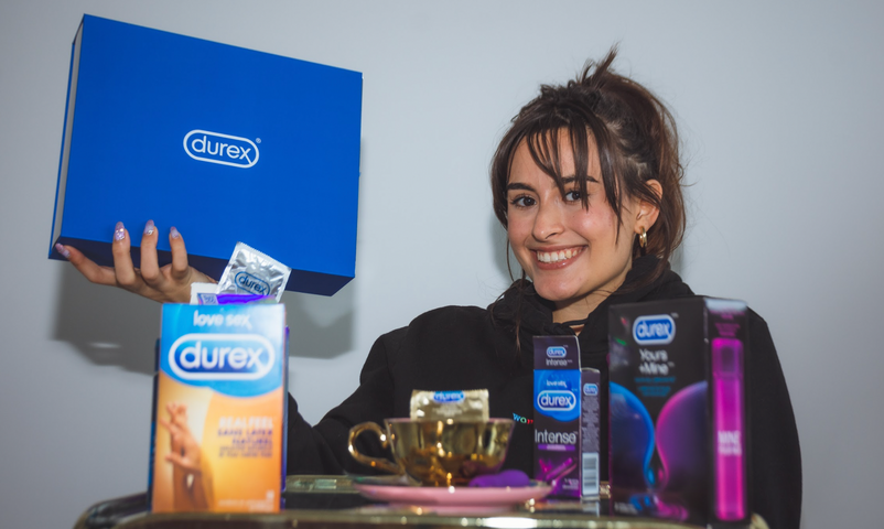 Felicia from The Sex and Self Podcast smiling into the camera among a variety of Durex products