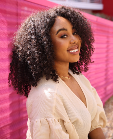 Portrait de Shadeen adossée à une clôture rose et souriant à l’appareil photo.