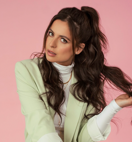 Headshot of Karine posing for the camera in front of a white and pink backdrop