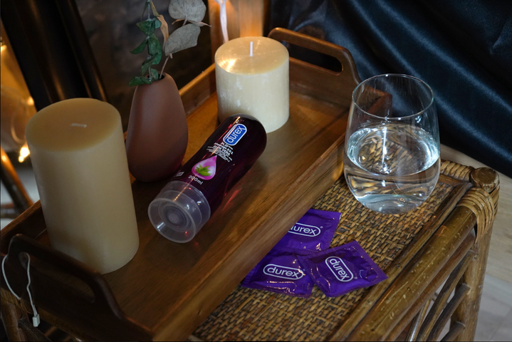 Des condoms Durex violets et Play Massage 2 en 1 Aloe vera sur une table de chevet.