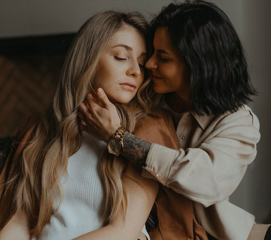 Two women embracing each other lovingly in a dimly lit setting