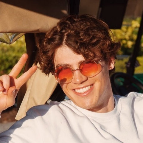 Guy wearing orange-tinted sunglasses smiling for the camera