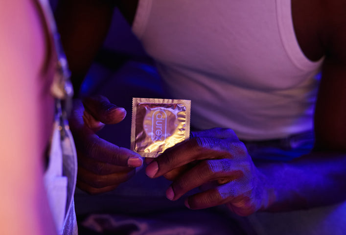 A person holds out a Durex Real Feel condom, a non-latex alternative to latex condoms