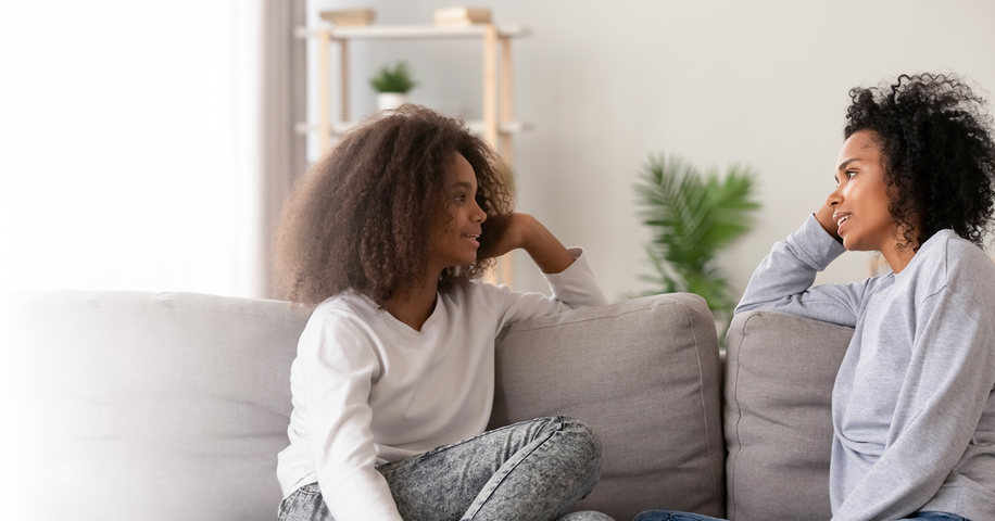 Mom and daughter sitting on sofa to discuss sexual health together. 