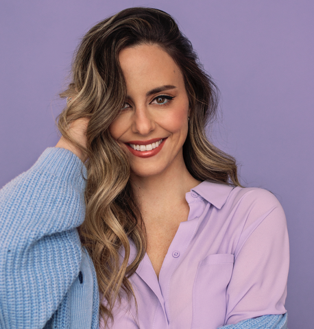 Headshot of Anne-Marie (Elle) smiling into the camera against a lavender backdrop