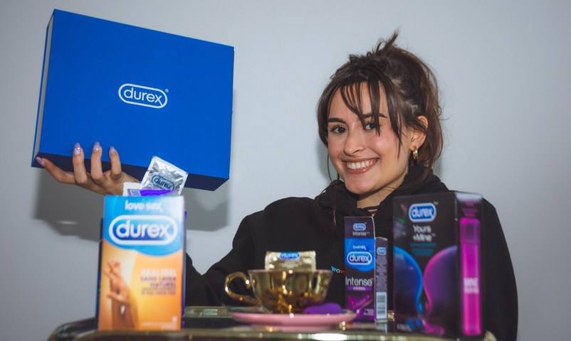 Felicia du balado Sex and Self souriant à l’appareil photo parmi une panoplie de produits Durex.
