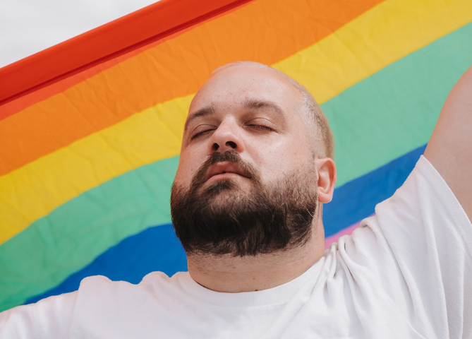 Karl Hardy closing his eyes in front of a pride flag
