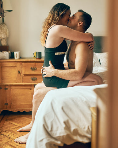 Un couple sur un lit qui s’embrasse en souriant et en s’étreignant.