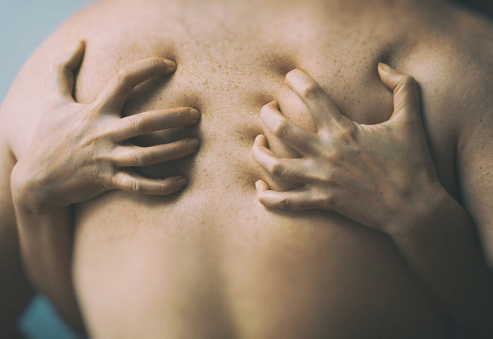 Fingers digging into a person's bare back.