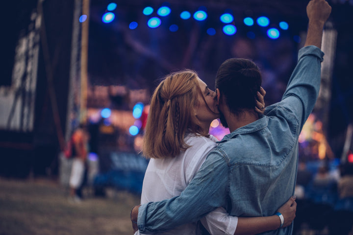 Une femme embrassant son partenaire sur la joue lors d’un événement estival en plein air.
