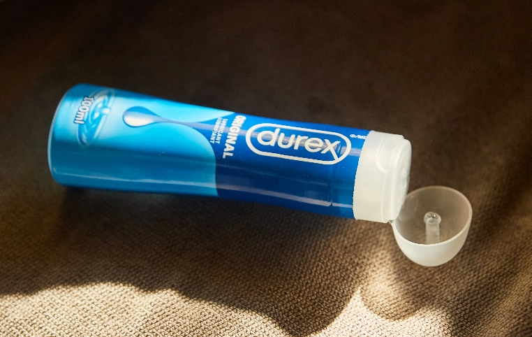 Une bouteille de lubrifiant Durex Original ouverte sur un tissu beige.