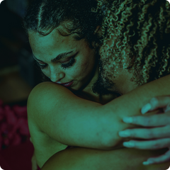 Couple hugging one another while a dim green light illuminates them.