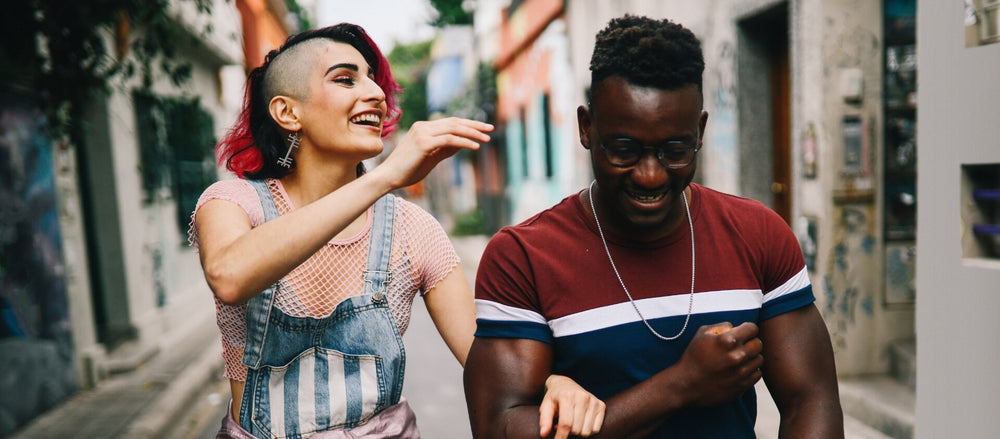 Woman and man linking arms while laughing together during an outdoor stroll