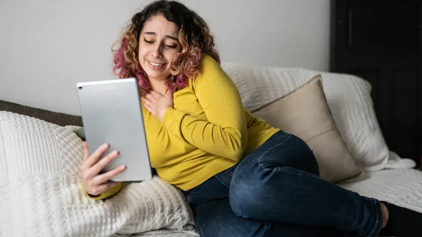 Woman holding her heart during a tender moment with her lover over a video call.